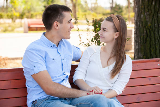 istock Young couple sitting on bench in park. 1161111636