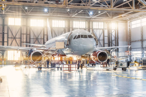vista all'interno dell'hangar dell'aviazione, il meccanico dell'aereo che lavora intorno al servizio. - aerospace industry foto e immagini stock