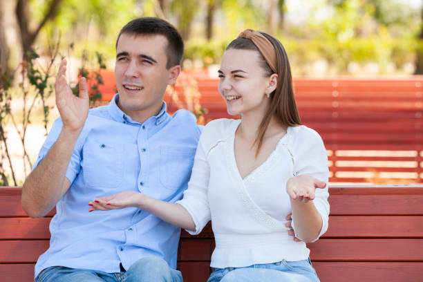 istock Young couple sitting on bench in park. 1161112878