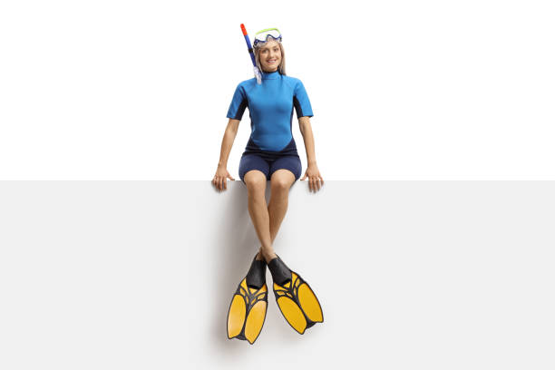 Full length portrait of a young woman with a diving equipment sitting on a panel isolated on white background