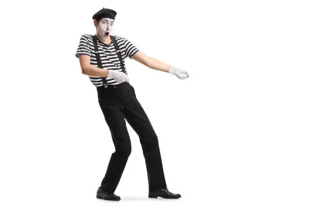 Full length shot of a mime pretending to pull a rope isolated on white background