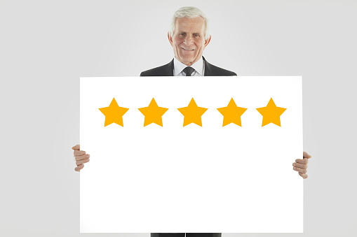 Businessman holding white sign with five stars on it. Clipping path on the sign.