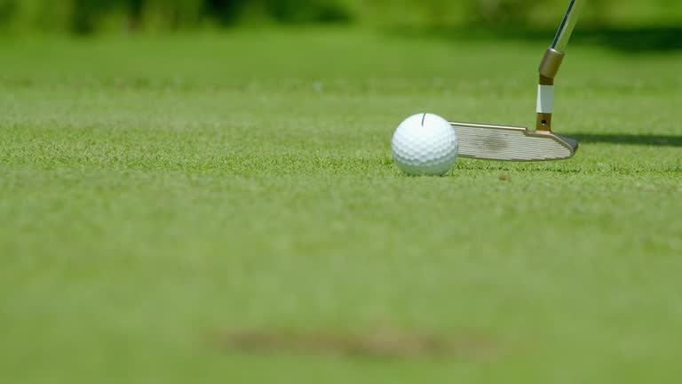 Slow motion rack focus shot of a golfer sinking a putt.