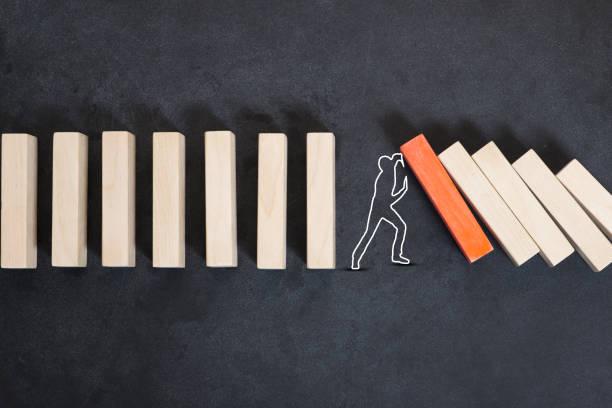 istock Man silhouette stopping domino effect on dark background or chalkboard 1161116738
