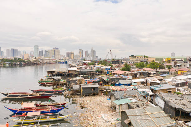 manila baraccopoli sullo sfondo di una grande città. case e barche dei poveri abitanti di manila. contrasto degli strati sociali - manila apartment poverty slum foto e immagini stock