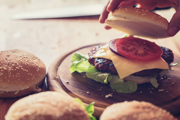 istock Burger making, close-up, hand holding burger bun 1161120235