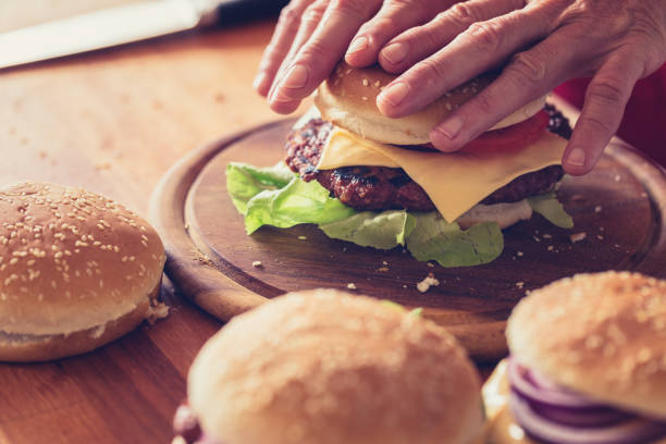 istock Burger making, close-up, hand holding burger bun 1161120236