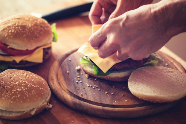 istock Hamburger preparing, sheet of soft cheese put on burger bun, close-up 1161120258