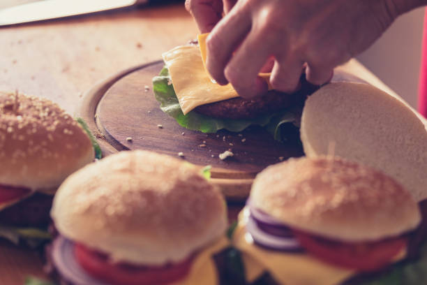 istock Hamburger preparing, sheet of soft cheese put on burger bun, close-up 1161120261
