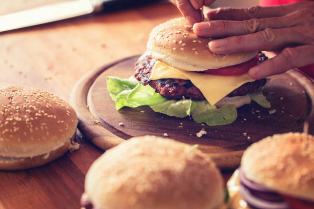 istock Burger making, close-up, hand holding burger bun 1161120309