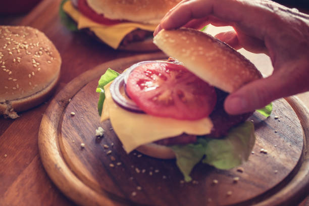 istock Burger making, close-up, hand holding burger bun 1161120311