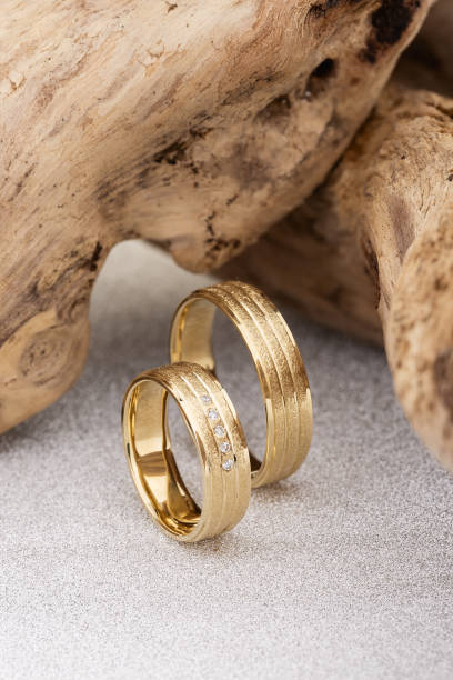 istock Pair of textured surface gold wedding ring bands on wooden background 1161120400