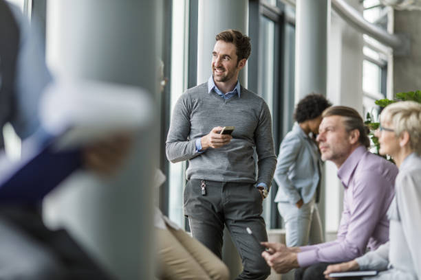 istock Happy businessman using mobile phone in a hallway with his colleagues. 1161120740