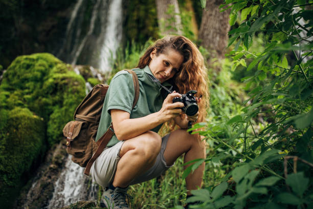 istock Lady biologist taking pictures with camera by the waterfall 1161121837