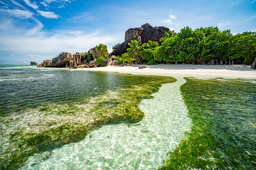 welcome to tropical paradise with clear water sand beach and granite rocks on sunny vacation day