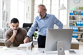 Senior manager explaining to coworker something on computer