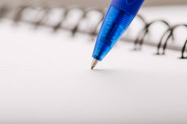Opened notepad in a cage with an automatic plastic ballpoint pen close-up.