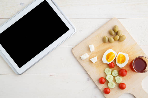 istock tablet,tea and Turkish,Mediterranean Breakfast before the start of the working day or while working on a light wooden tray on a white natural background. the view from the top 1161128178