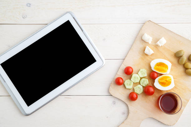 istock tablet,tea and Turkish,Mediterranean Breakfast before the start of the working day or while working on a light wooden tray on a white natural background. the view from the top 1161128307