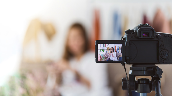 Beautiful asian woman blogger is showing shopping clothes and dress. In front of the camera to recording vlog video live streaming at home.Business online influencer on social media concept.