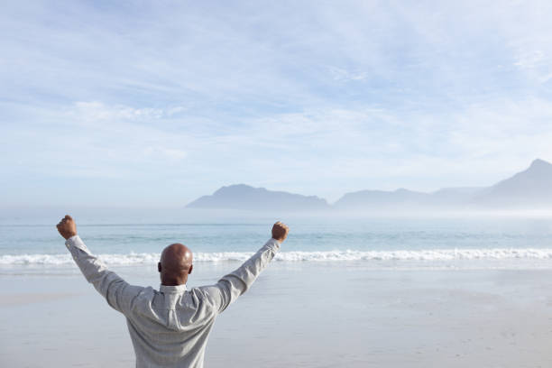 istock Man with arms raised on the beach 1161140088