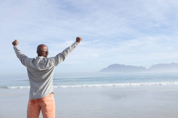 istock Man with arms raised at the beach 1161140247