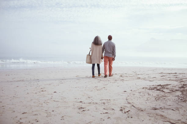 istock Couple holding hands while walking by the beach 1161143409