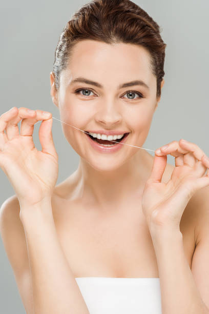 istock happy woman flossing teeth with dental floss isolated on grey 1161143552