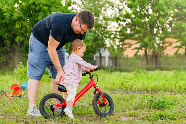 Young father spend time with Cute little one years old toddler girl child and balance bike, father's day stock photo