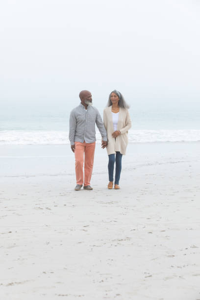 istock Couple holding hands while walking by the beach 1161145778