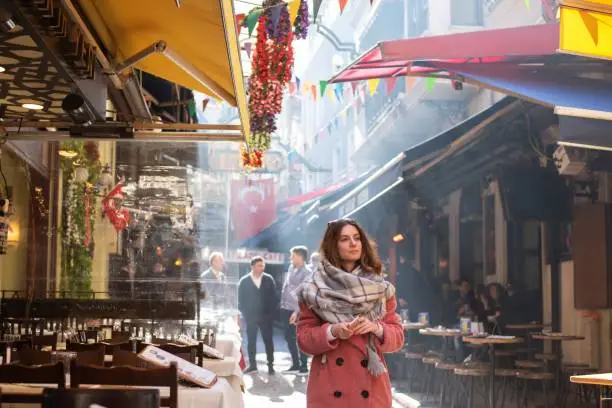A mid adult woman in winter clothes exploring Istanbul's various landmarks.
