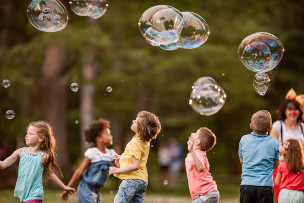 istock Group of kids having fun while catching rainbow bubbles in springtime. 1161147362