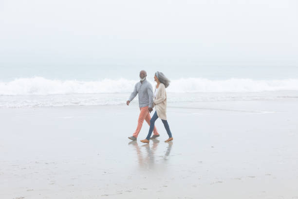 istock Couple holding hands while walking by the beach 1161148109
