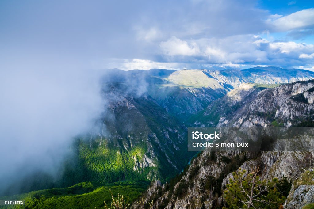 Montenegro, Wet rain clouds coming quickly over tara river canyon nature scenery at dawn from above mountain top curevac providing endless view over rocky gorge Atmospheric Mood Stock Photo