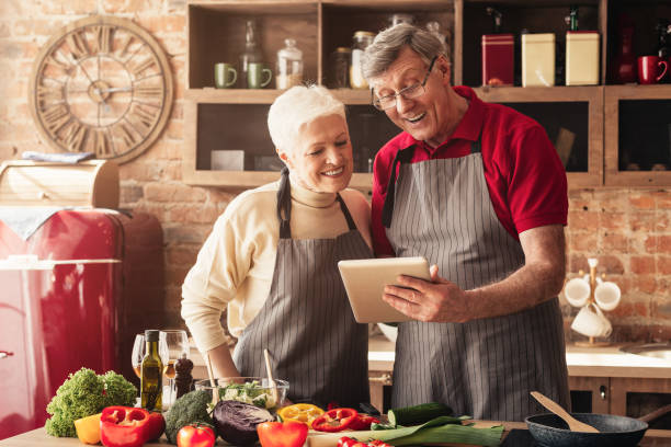 istock Senior couple reading recipe on digital tablet at kitchen 1161149856