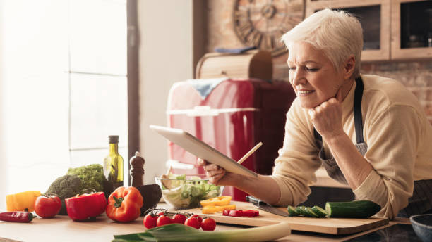 istock Dreamy senior housewife browsing on digital tablet at kitchen 1161150876
