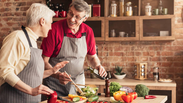 istock Laughing seniors cooking vegetable salad at kitchen 1161151057