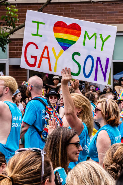 A mother carries a sign that reads "I <heart> my gay son" while marching in the Gay Pride parade. stock photo