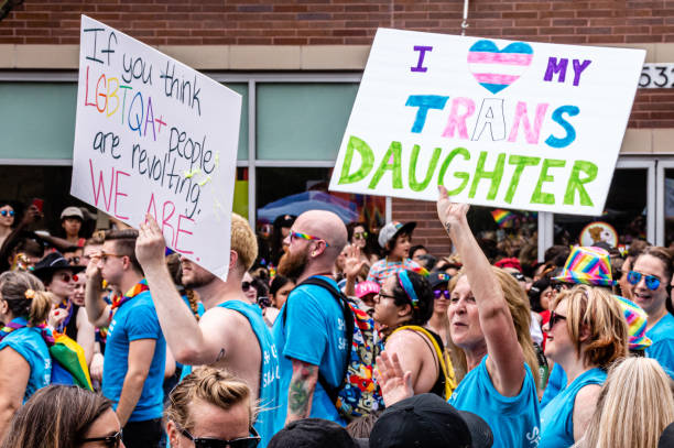 A mother carries a sign that reads "I <heart> my trans daughter" while marching in the Gay Pride parade. stock photo