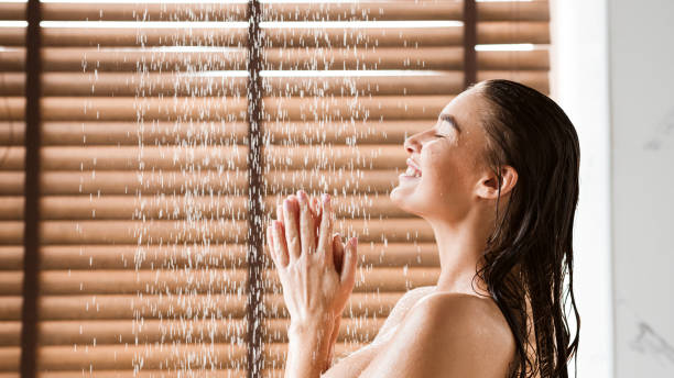 vrouw nemen douche genieten van water spatten op haar - douchen stockfoto's en -beelden