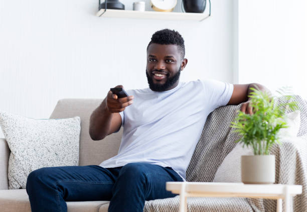 istock Young african american man watching TV at home 1161154811