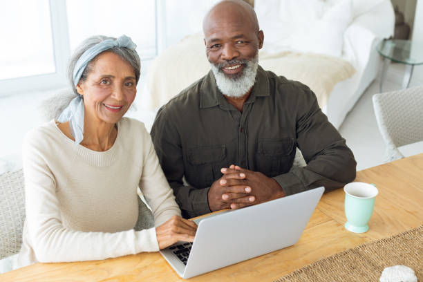 istock Couple smiling while using white laptop on table and the man holds a cup 1161156654