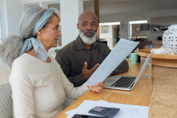 istock Couple discussing papers and using laptop inside a room 1161156798