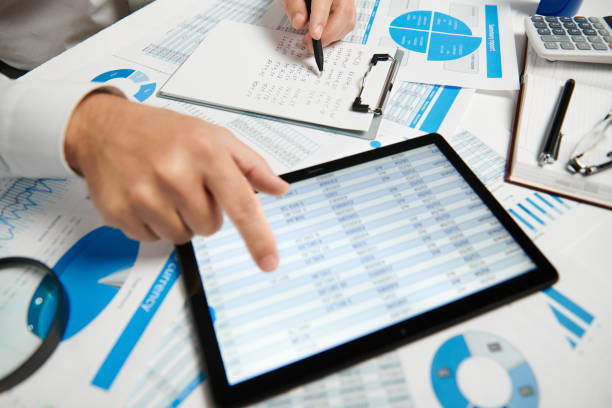 istock Businessman working and calculating, reads and writes reports. Using tablet pc. Office employee, table closeup. Business financial accounting concept. 1161157651