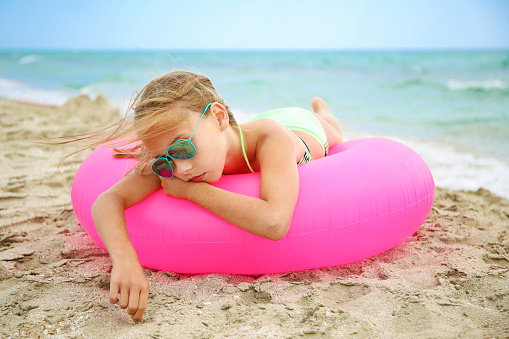 Sad girl lying on pink inflatable circle.