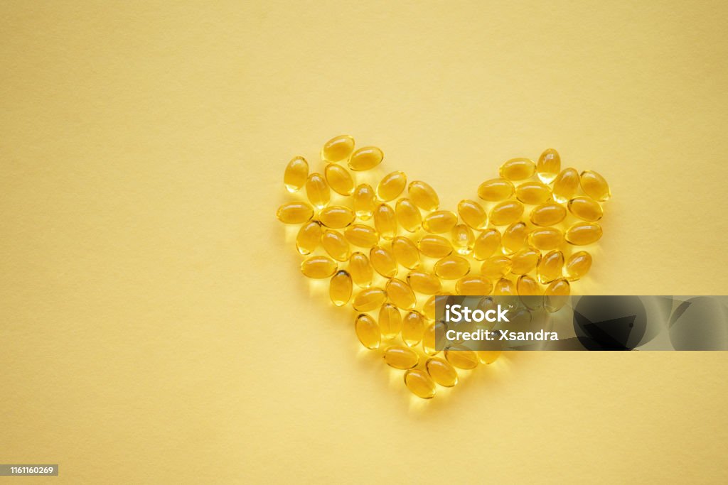 Gelbe Nahrungsergänzungsmittel Pillen in Herzform auf gelbem Hintergrund - Lizenzfrei Fischöl Stock-Foto