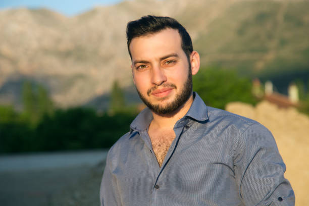 Portrait of  young man looking at camera against tree area