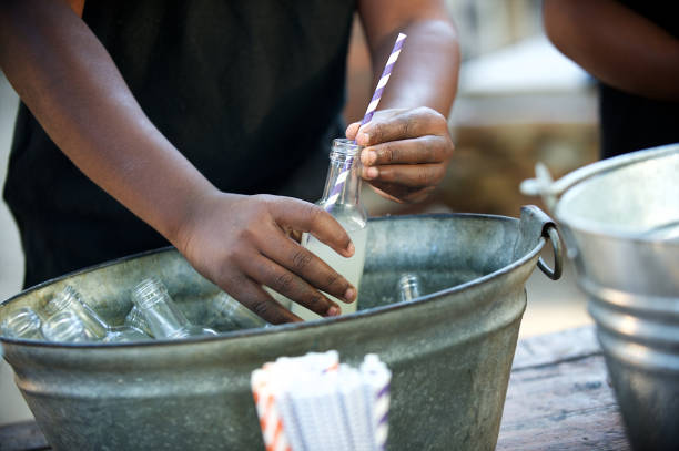 Hands inserting a drinking straw in a cold drink of fresh ginger beer
