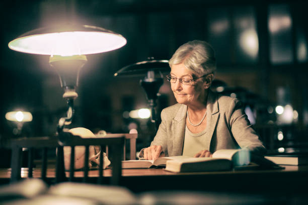 Senior woman reading in library at night