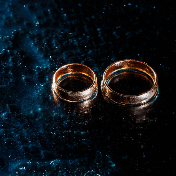 istock Beautiful wedding gold rings on dark background 1161168988